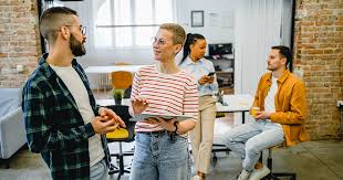 Two coworkers having a casual conversation in an open office
