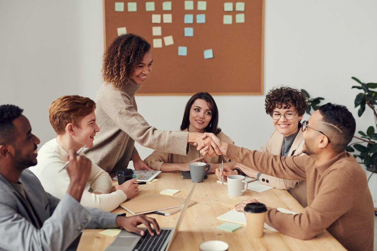 Colleagues shaking hands across a meeting table