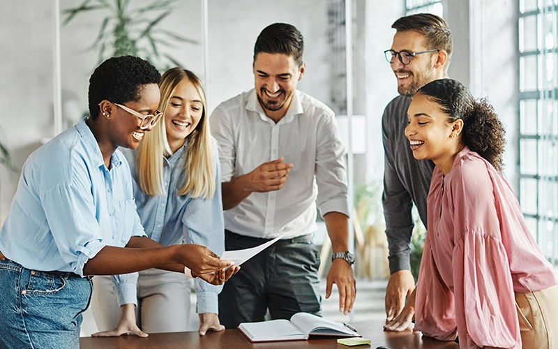 Colleagues laughing together while reviewing a document
