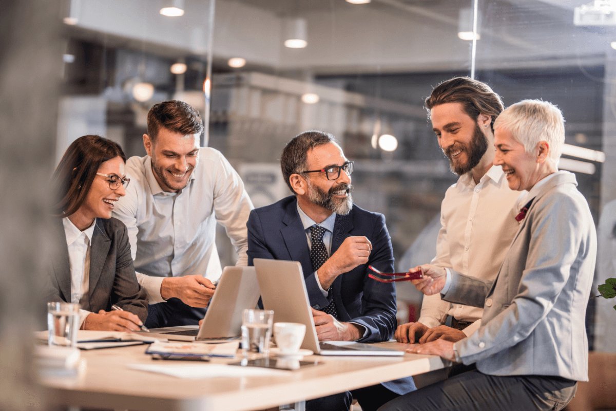 A team of colleagues laughing together around a laptop